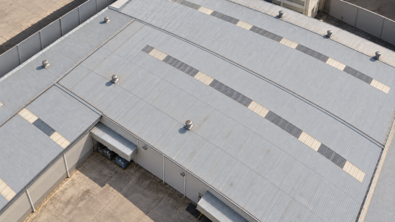 Vista aérea de uma fábrica de confecção de médio porte, com telhados industriais e pátio interno, sem identificação comercial.